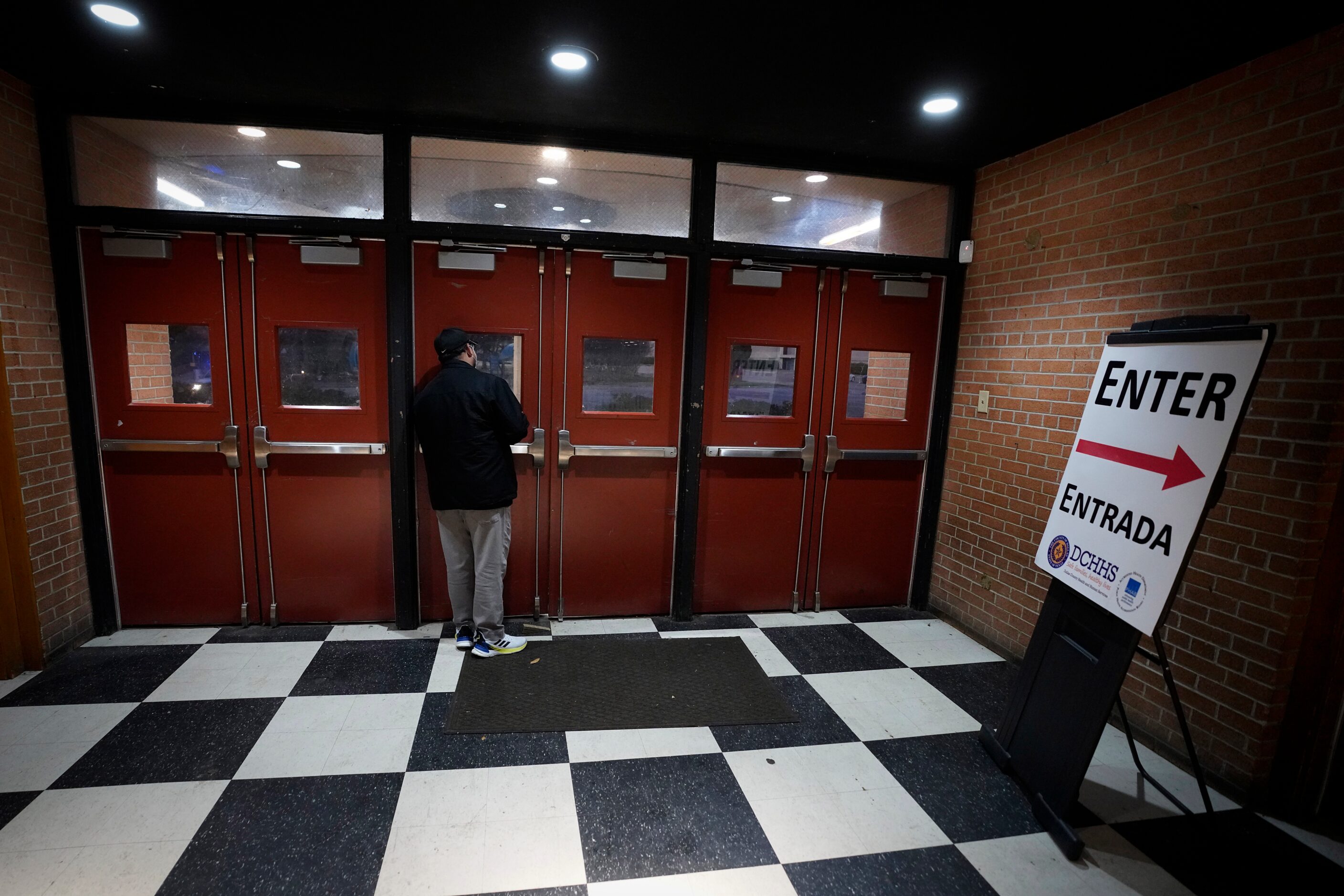 A Dallas County Health and Human Services employee waits for the doors to open for people to...