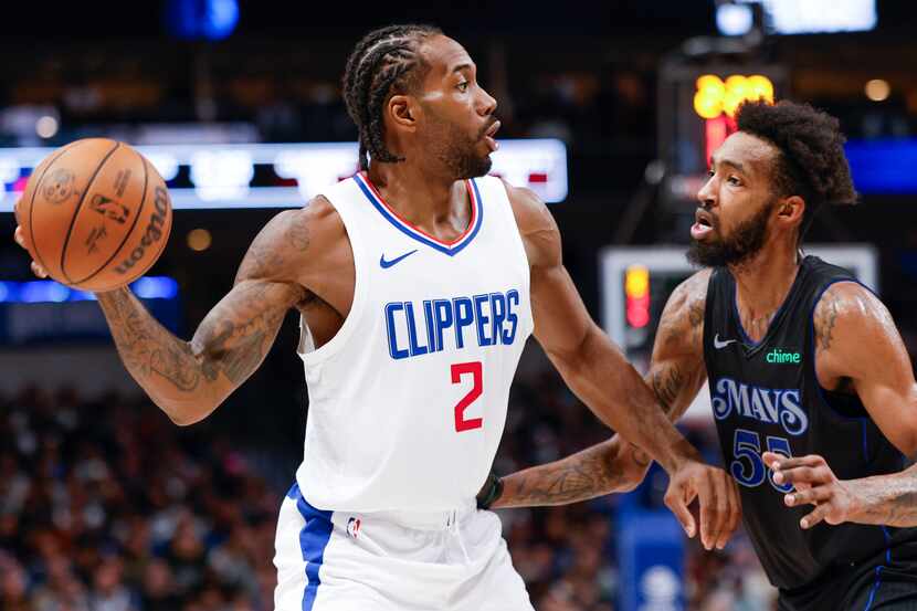 LA Clippers forward Kawhi Leonard (left) looks to pass past Dallas Mavericks forward Derrick...