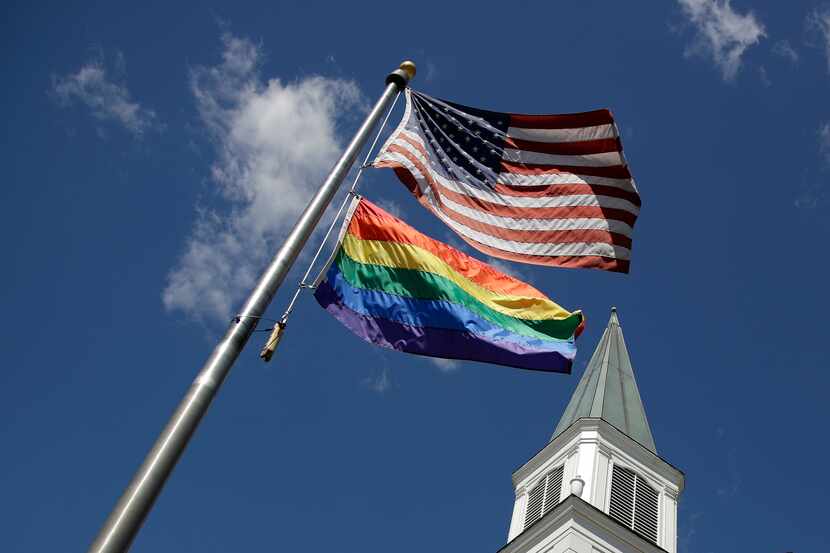A gay pride rainbow flag flies with the U.S. flag in front of the Asbury United Methodist...
