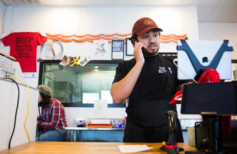 Isaiah Chavoya (right), of butcher shop Deep Cuts Dallas, takes a phone order on Sunday,...