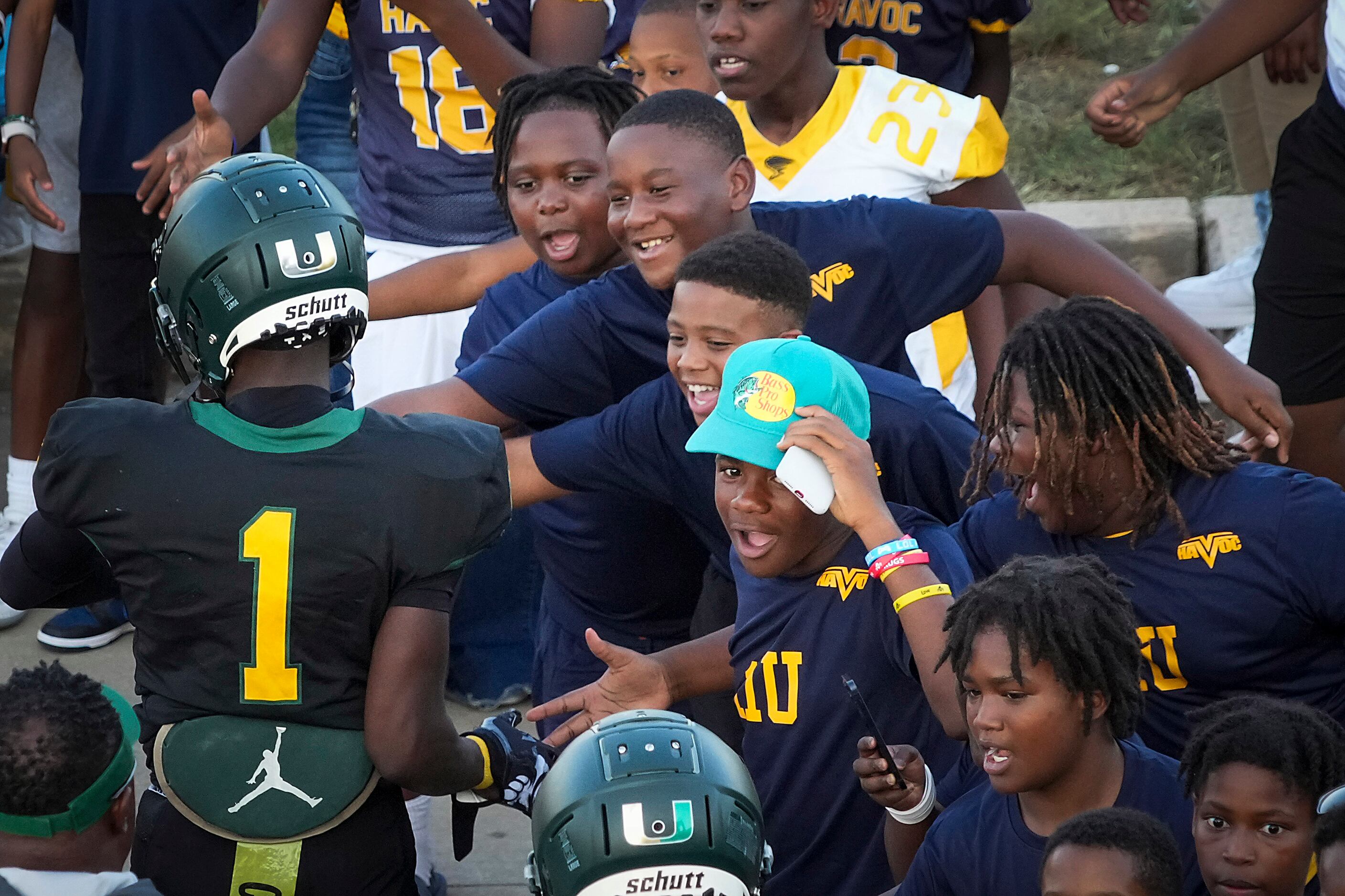 DeSoto wide receiver Johntay Cook II (1) slaps hands with youngsters as the team takes the...