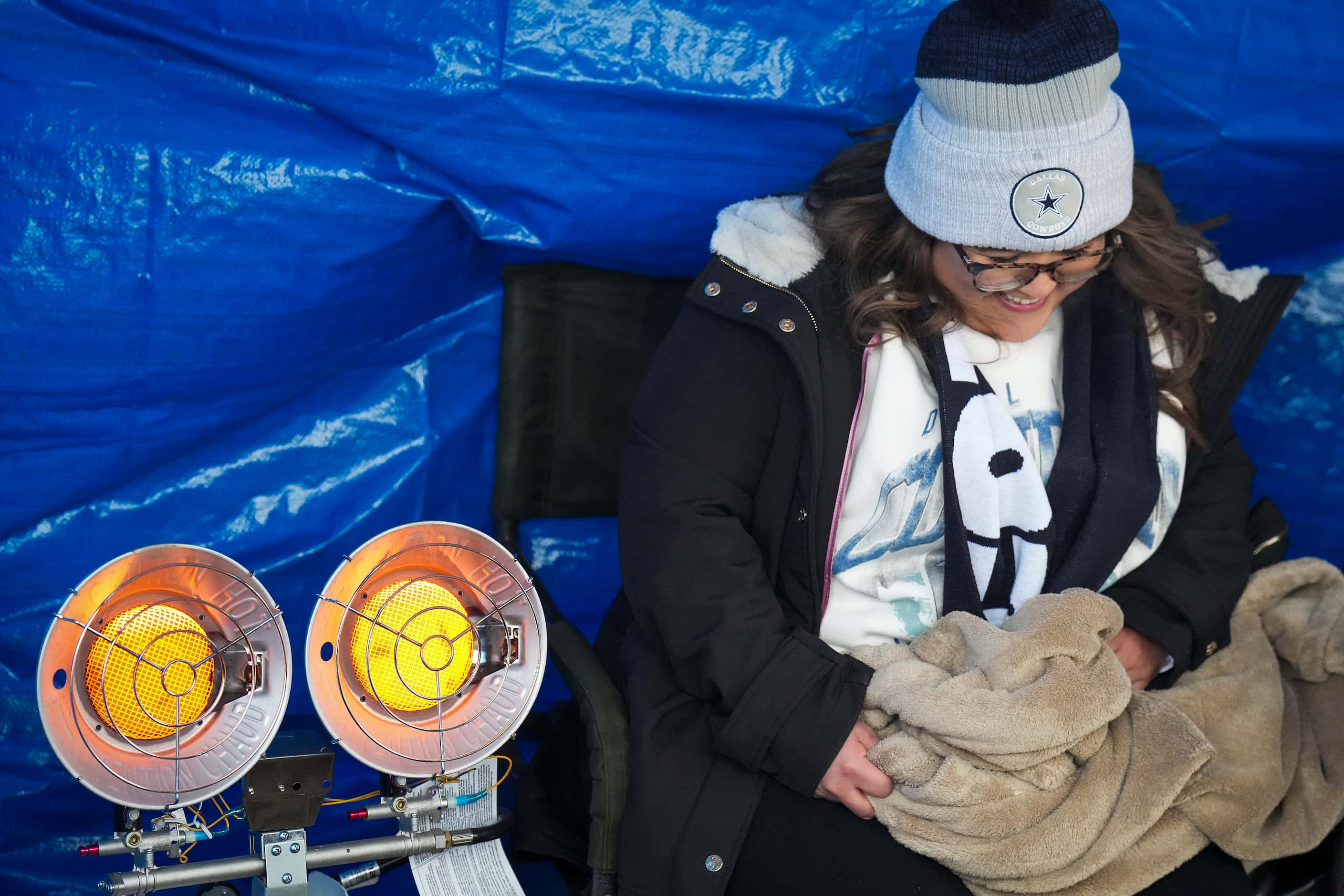 Dallas Cowboys fan Kami Reyes huddles next to a heater while tailgating before an NFL...