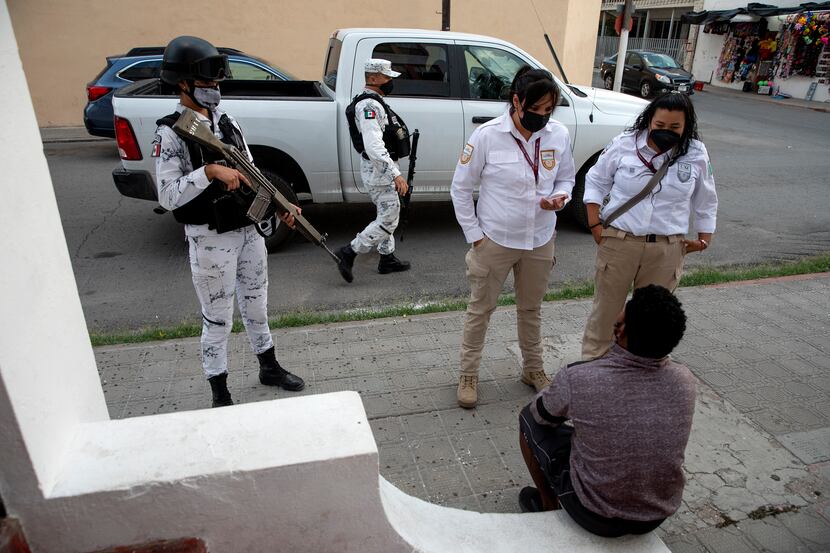 Mexican immigration officials and the Mexican National Guard talk to migrants at the Hotel...