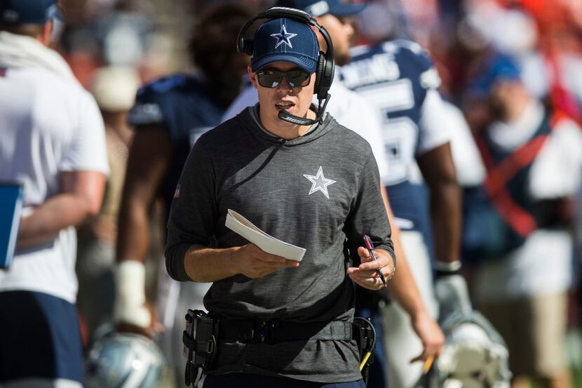 Dallas Cowboys offensive coordinator Kellen Moore talks on his headset on the sideline...