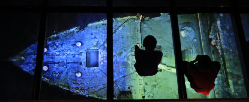 Two children look down at a image of the Titanic wreck in the Titanic Belfast visitor center...
