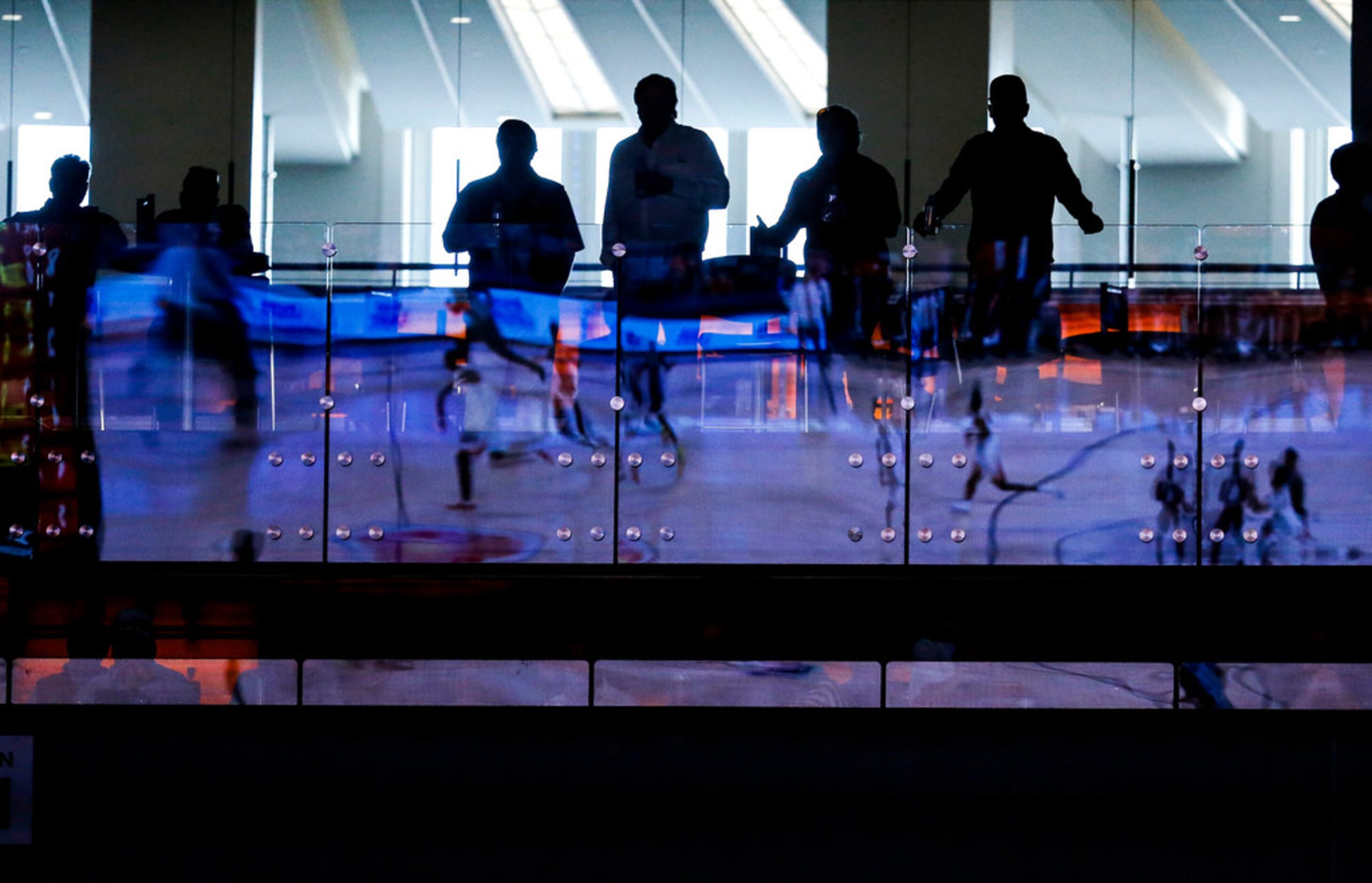 Fans watch from above as the game is reflected in a glass divider during the second half of...