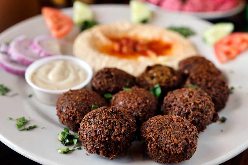 The falafel plate served with homemade hummus made with chickpeas and topped with paprika is...