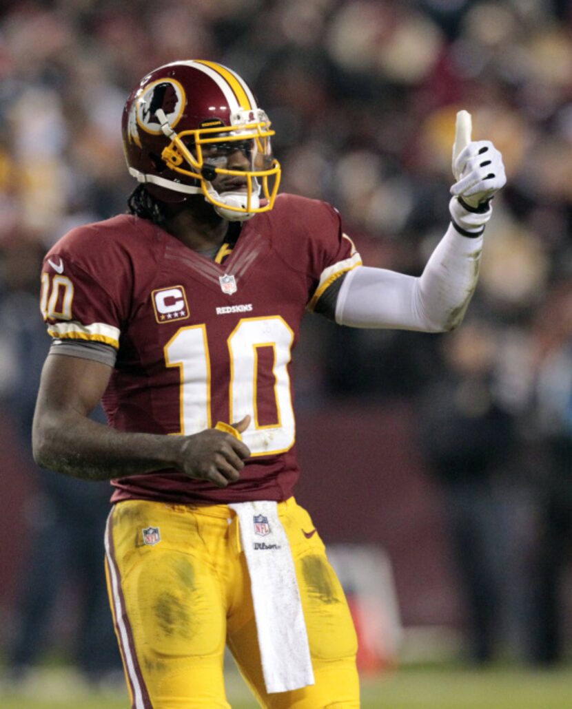 Washington Redskins quarterback Robert Griffin III (10) signals thumbs up during a break in...