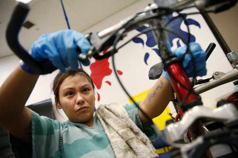 Patricia Greer works on a bicycle's brakes at Lew Sterrett Justice Center in Dallas, where...