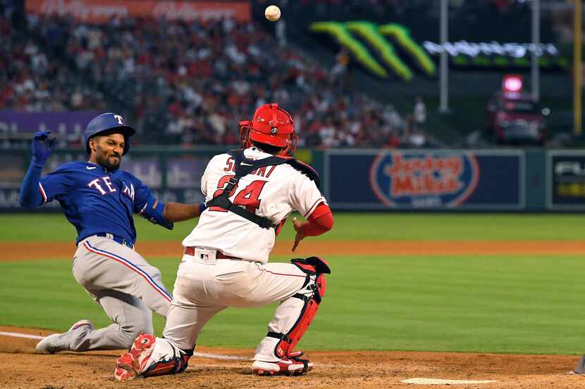Texas Rangers' Marcus Semien, left, scores after hitting a double and then advancing to home...