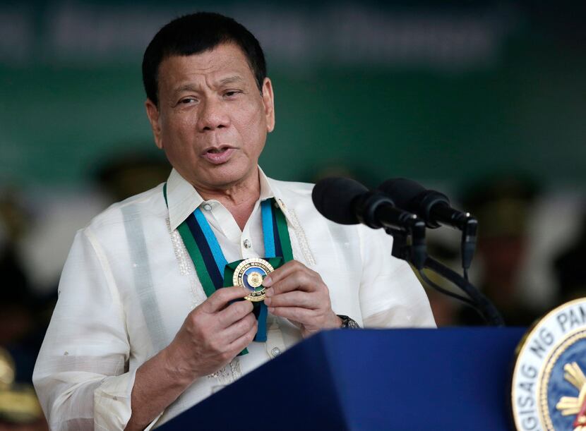 Philippine President Rodrigo Duterte shows a medal during his speech to troops during the...