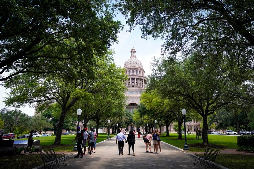 People walk on the grounds of the Texas Capitol during the 87th Texas legislature on Friday,...
