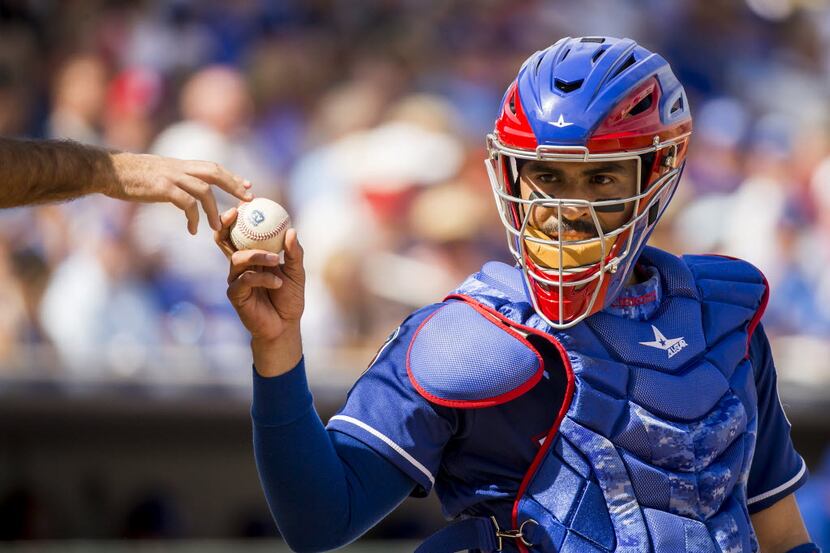 Texas Rangers catcher Robinson Chirinos gets a new ball from the umpire during a spring game...