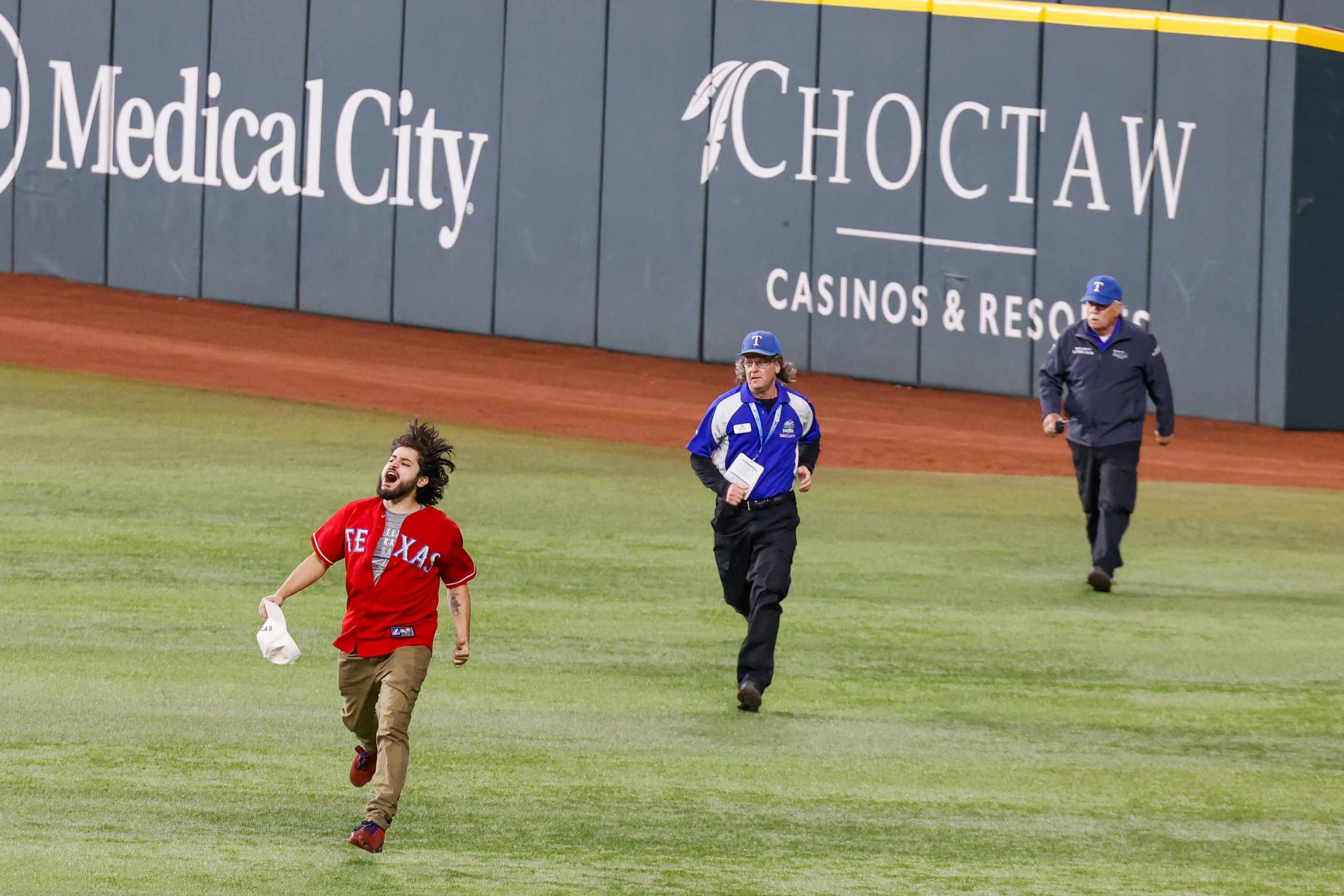 Security chases after a fan who ran onto the field following Texas Rangers’ winning the...
