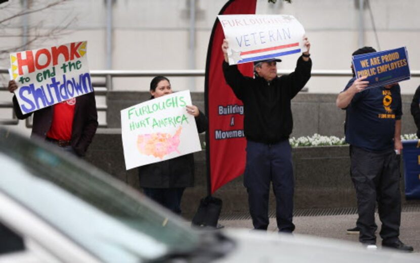 Empleados federales en Dallas muestran pancartas pidiendo apoyo para el fin del cierre del...