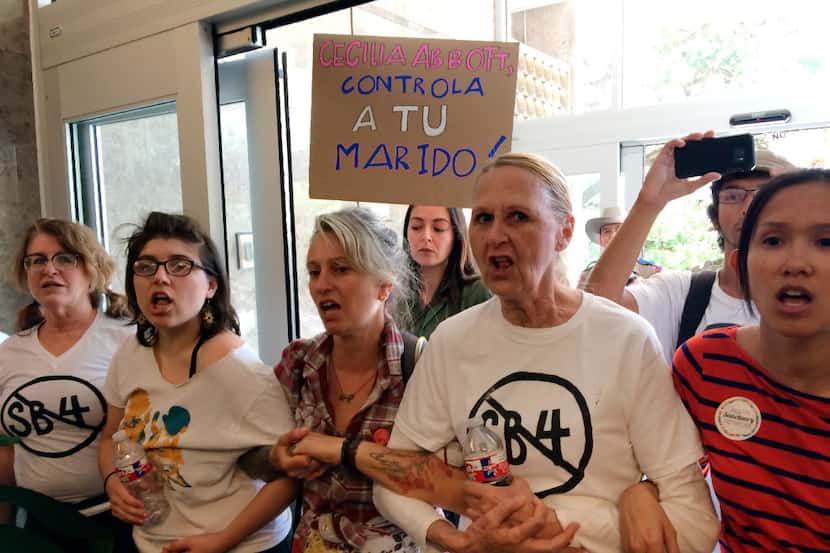 A group of protesters rally during a sit-in at the Texas Department of Insurance building in...