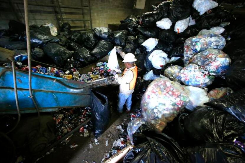 
Gilbert Chavez empties trash bags of cans for recycling at Jacobs Iron and Metal. The...