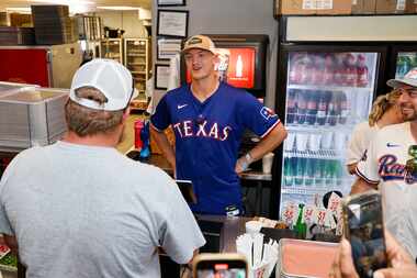 Texas Rangers third baseman Josh Jung rings up an order for a customer at the register at...