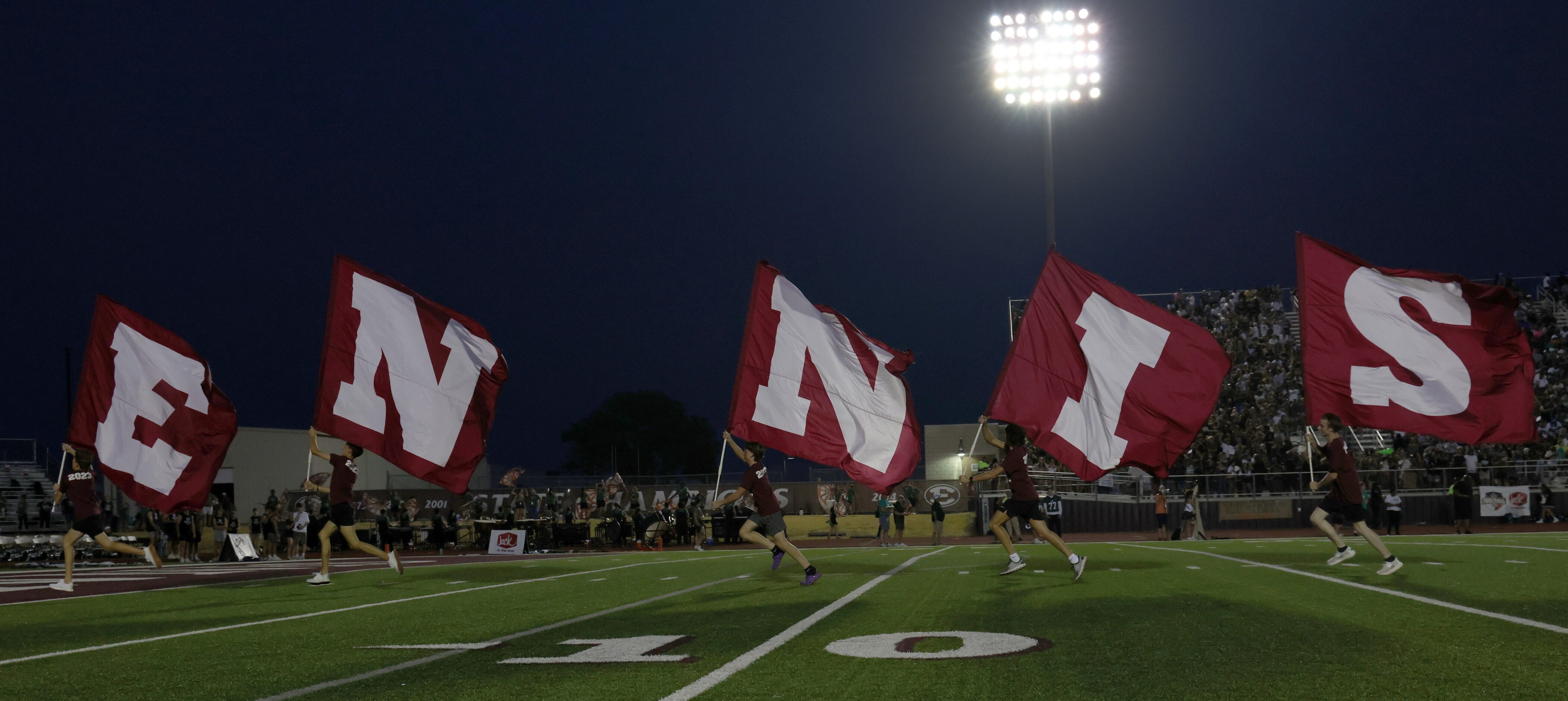 Members of the Ennis flag corps race across the field following a Lions touchdown during...