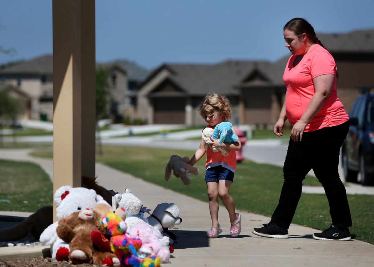 Judith McDuffie, 4, carries stuffed animals to place at a memorial with her mother Amanda...