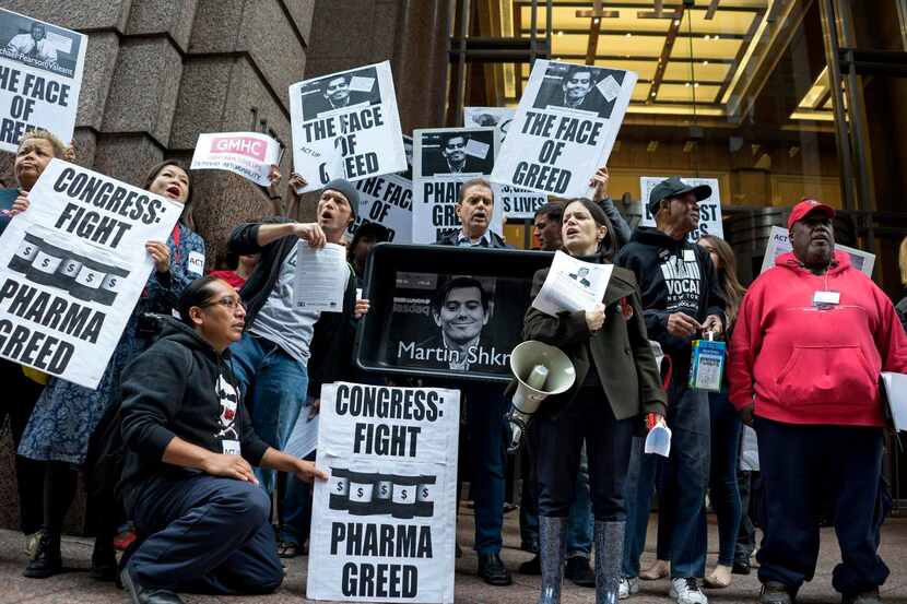 
Activists hold signs containing the image of Turing Pharmaceuticals CEO Martin Shkreli in...