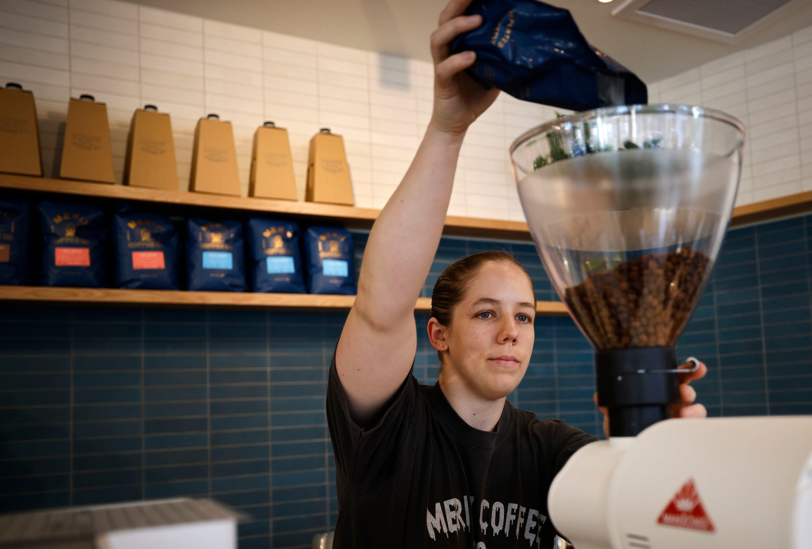 Claire Minor, district manager, grinds coffee during a soft opening of a new Merit Coffee...