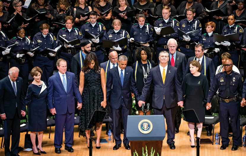 President Barack Obama joined hands with Dallas Mayor Mike Rawlings as they and other...
