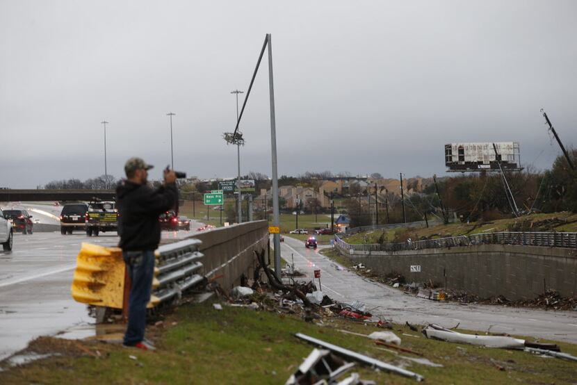  An onlooker takes pictures of the damage after a tornado hit last night in Garland, Texas...