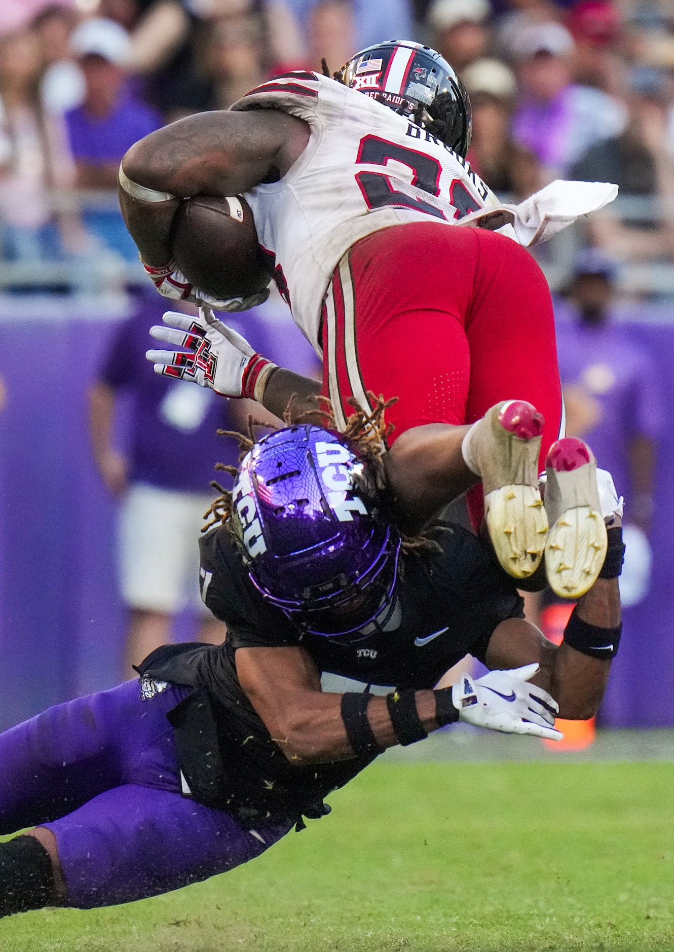 Texas Tech running back Tahj Brooks (28) is upended by TCU cornerback Channing Canada (7)...