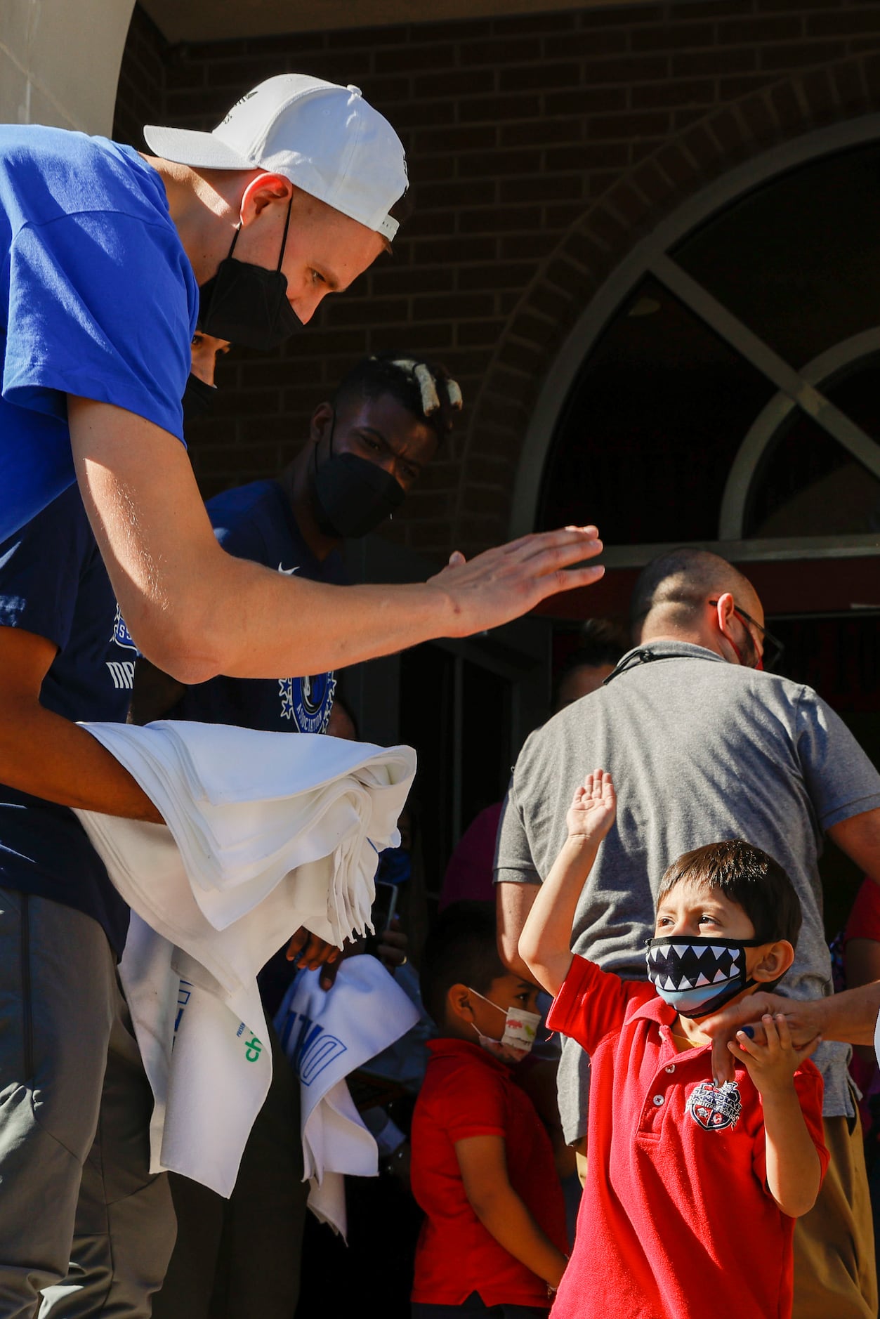 Dallas Mavericks center Kristaps Porzingis high-fives a student after the end of classes at...