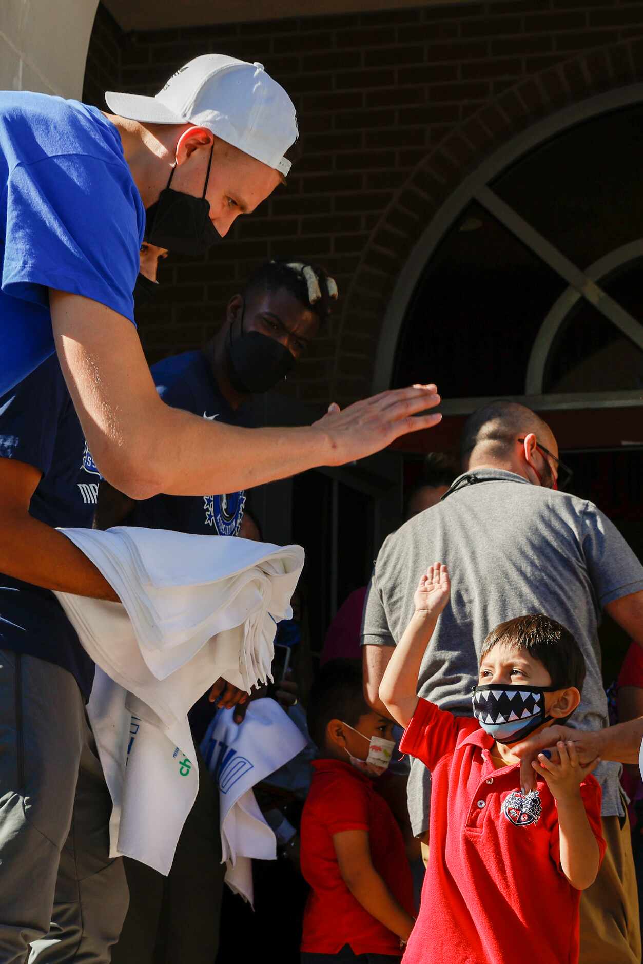 Dallas Mavericks center Kristaps Porzingis high-fives a student after the end of classes at...