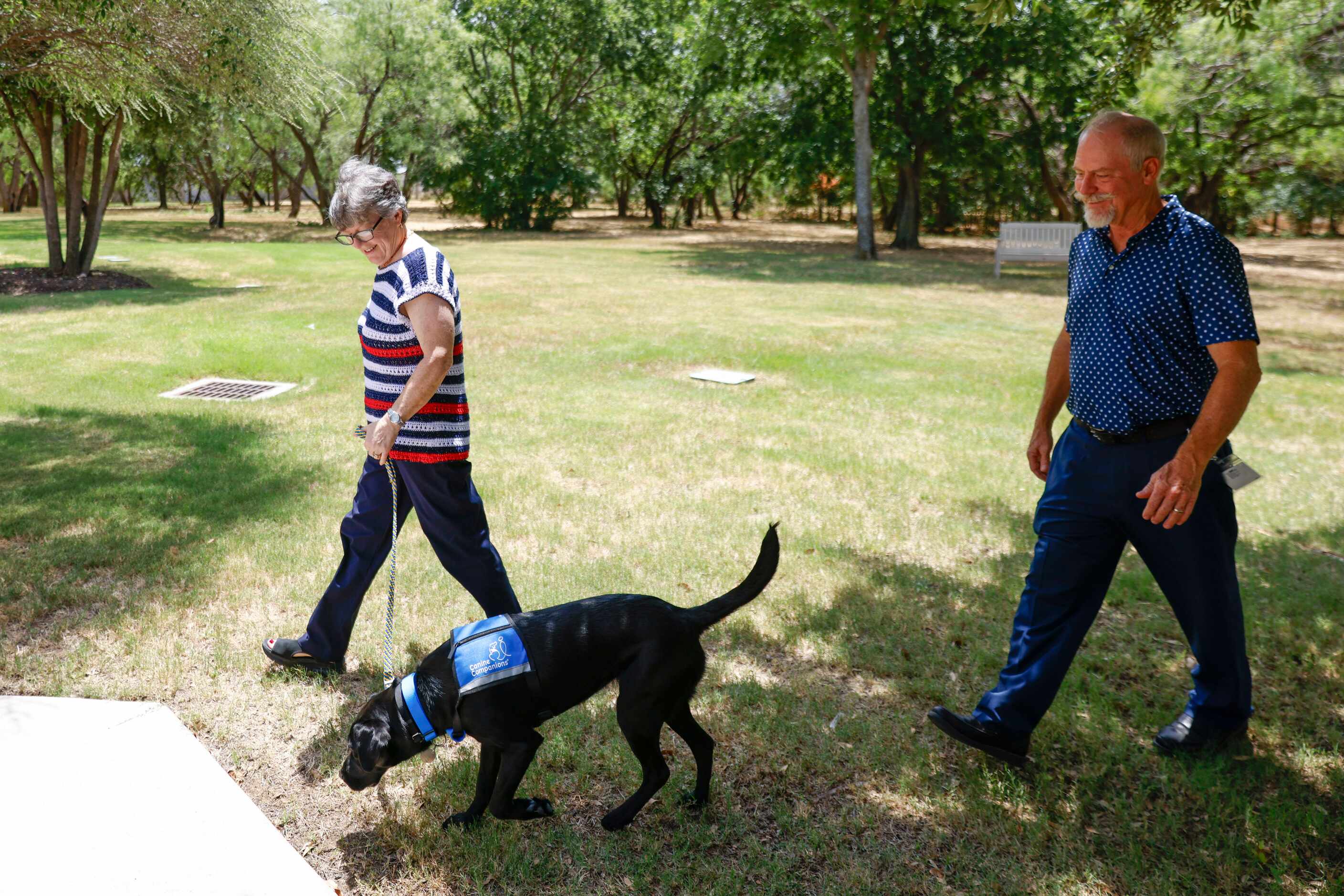 Veteran Kathy Schneider with her dog Dakota, and husband Ray walks back to the training...