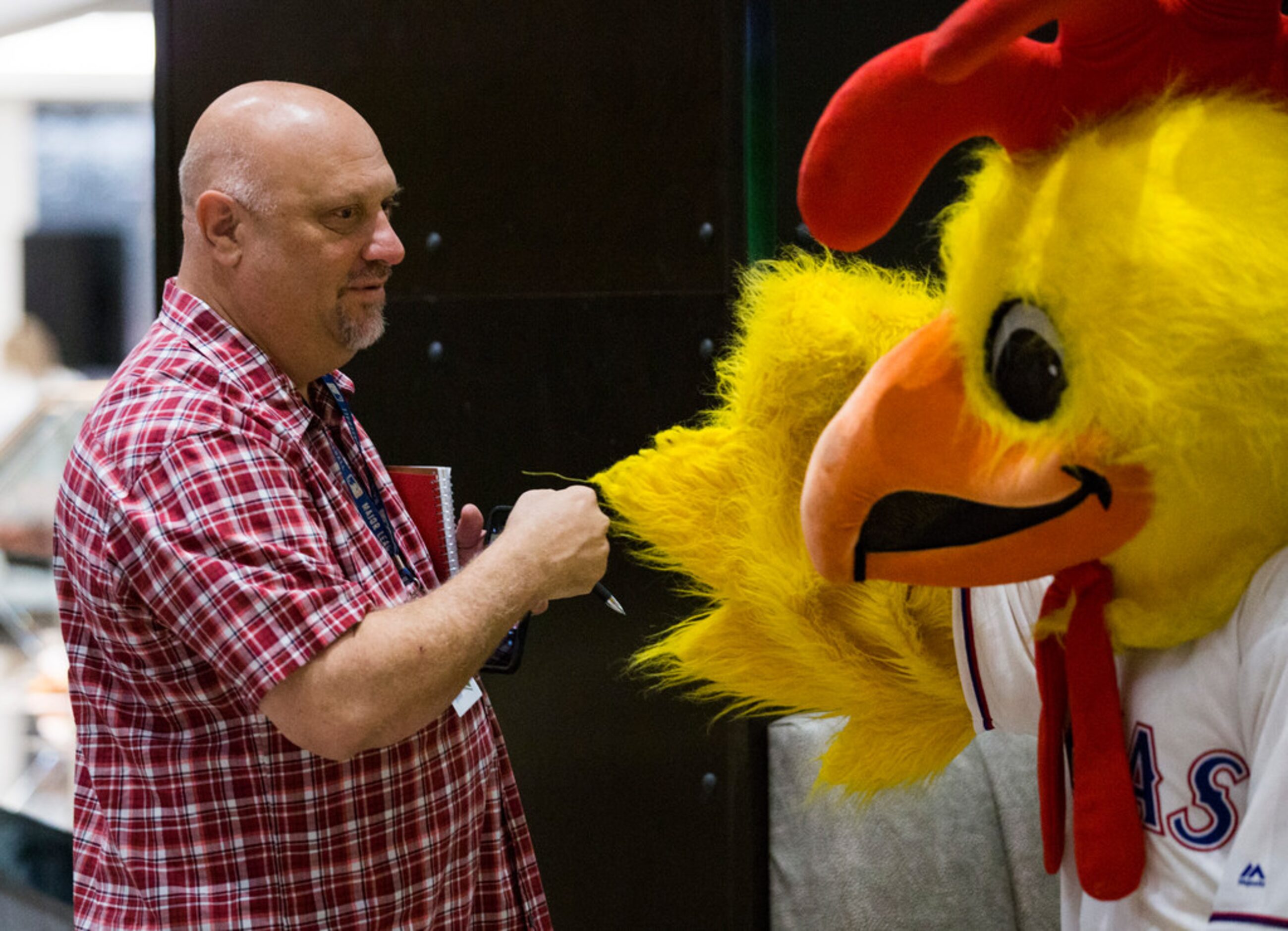 The Dallas Morning News' Evan Grant fist bumps a large chicken before sampling new...