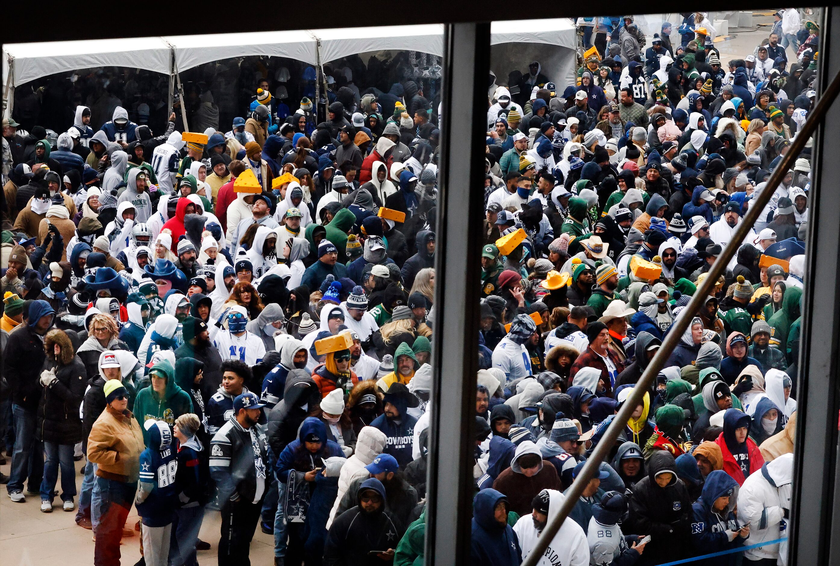 Dallas Cowboys and Green Bay Packers fans keep warm on the west plaza as they wait to get...