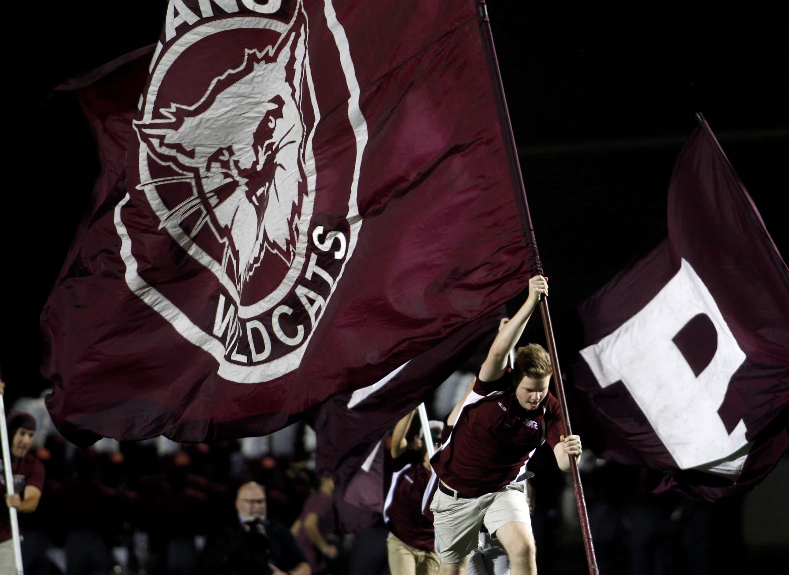 A member of a Plano spirit team races across the field with the school flag following a...