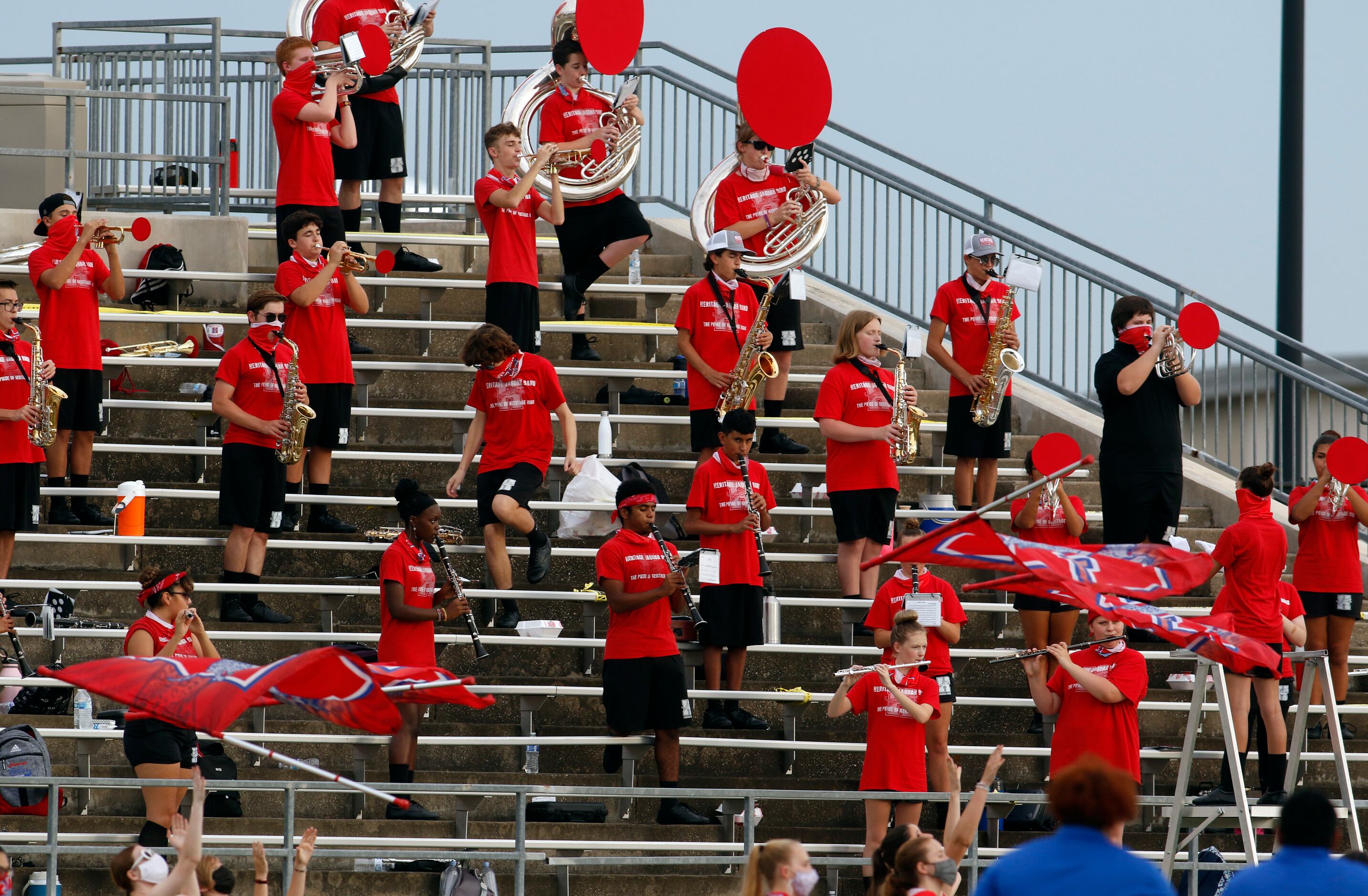 Members of the Midlothian Heritage high school band social distance while performing from...