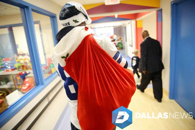 Dallas Cowboys wide receiver Dez Bryant carries a sack of gifts for patients during a visit...
