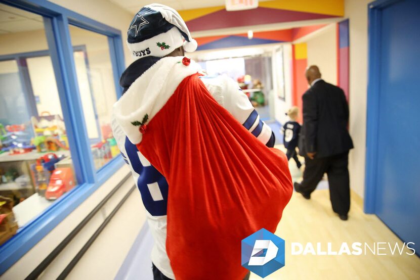 Dallas Cowboys wide receiver Dez Bryant carries a sack of gifts for patients during a visit...