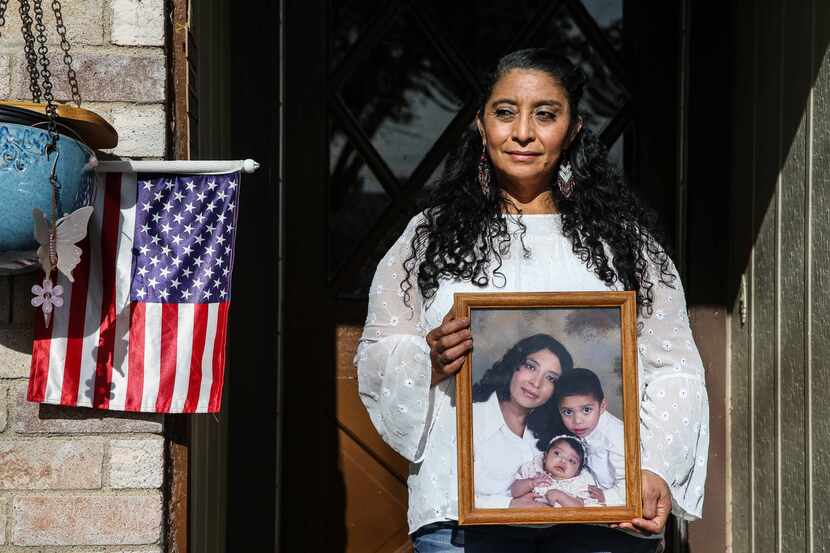 Dalila Sandoval poses in front of her home holding a photo of her and her two U.S.-born...