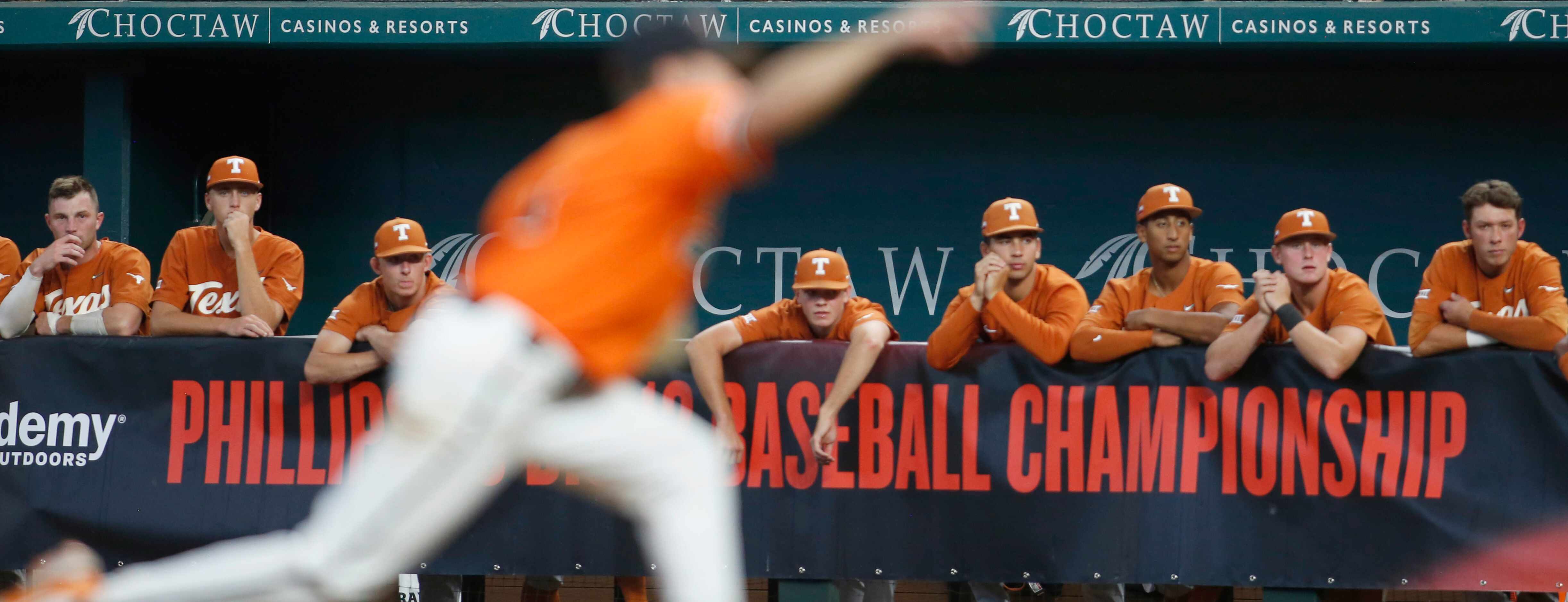 Texas Longhorns players watch from the team dugout as Oklahoma State pitcher Hueston Morrill...
