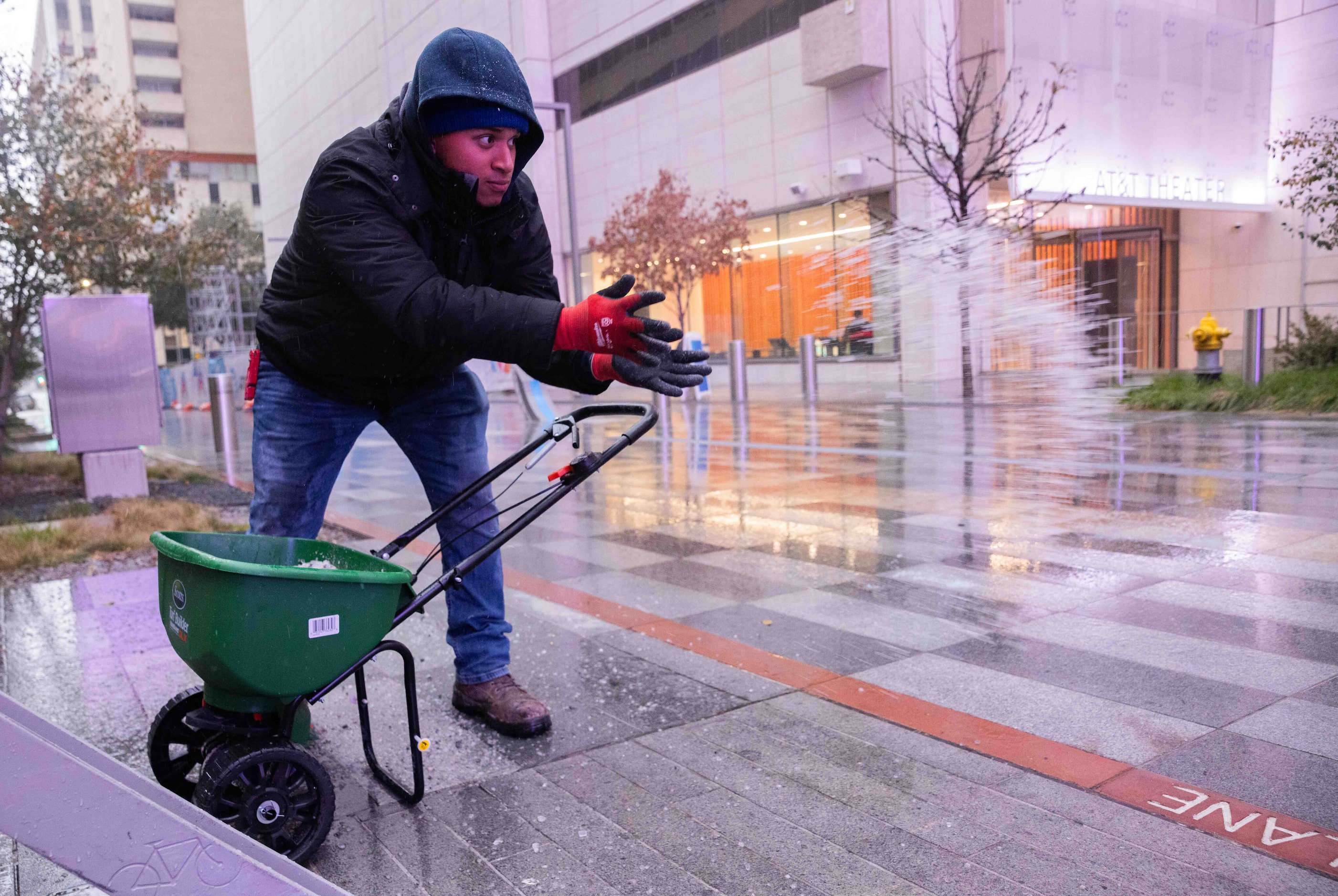 Eric Perez with NTX Landscaping Irrigation Snow Removal salts the sidewalk of the AT&T...