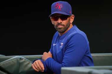 Texas Rangers manager Chris Woodward watches from the dugout during the ninth inning of a...