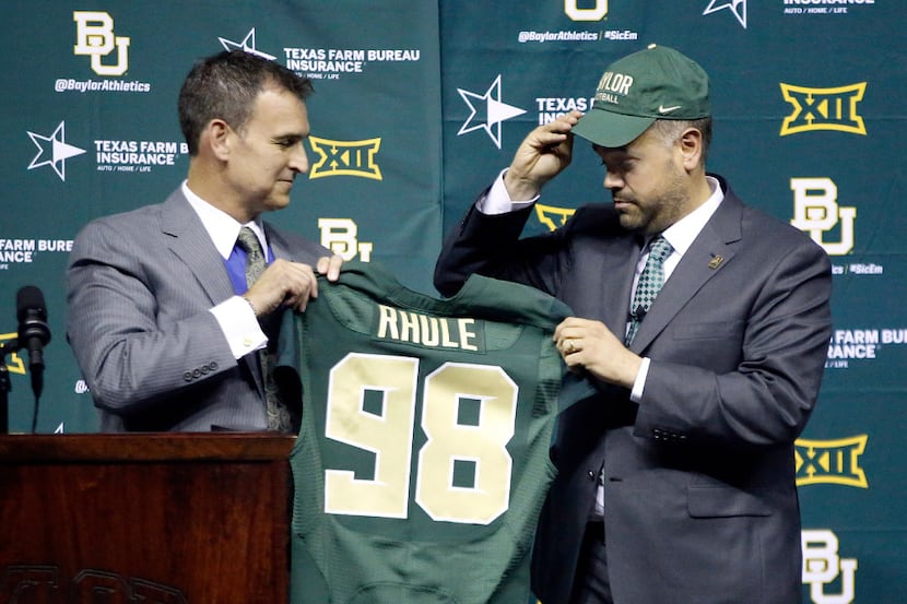 Baylor University's new head football coach Matt Rhule (right) dons the school hat and holds...