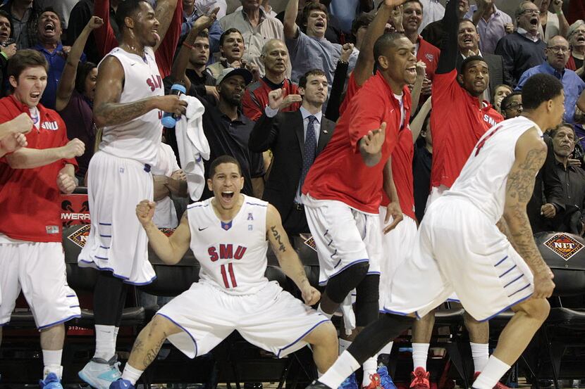 The SMU bench and SMU Mustangs guard Nic Moore (11) erupts following a three pointer by SMU...