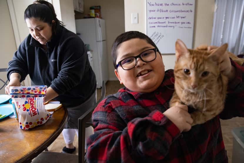 David Sanroman shows his cat Luna as mother Rosa Mendoza prepares him a peanut butter and...