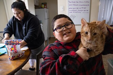 David Sanroman, 7, shows his cat Luna as mother Rosa Mendoza prepares him a PB&J sandwich...