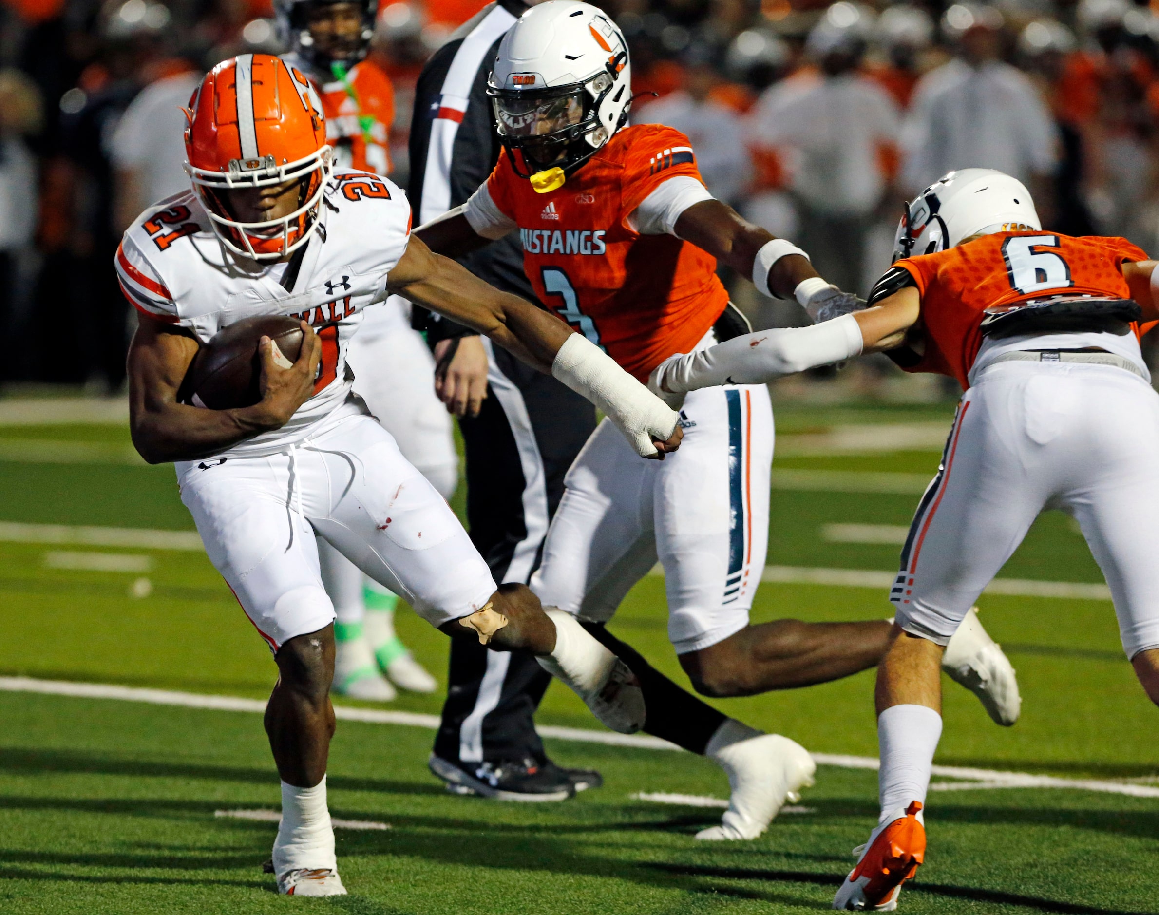 Rockwall High Jamir Wilson (21) spins out of the grasp of several Sachse High defenders...