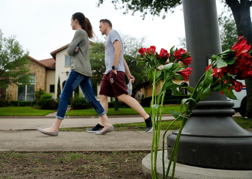 Neighbors walk past a small memorial outside the lakeside home of Lashun Massey in Irving.