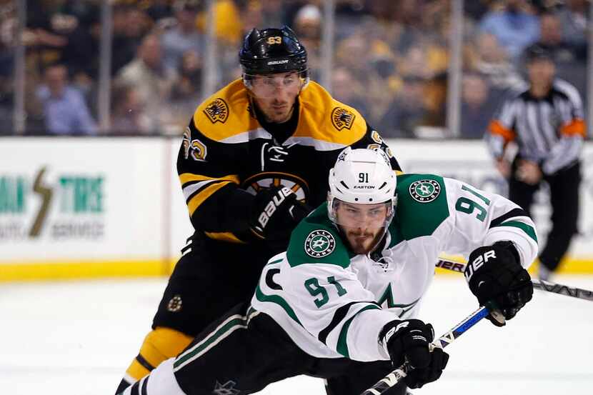 Dallas Stars' Tyler Seguin (91) falls as he brings the puck up in front of Boston Bruins'...