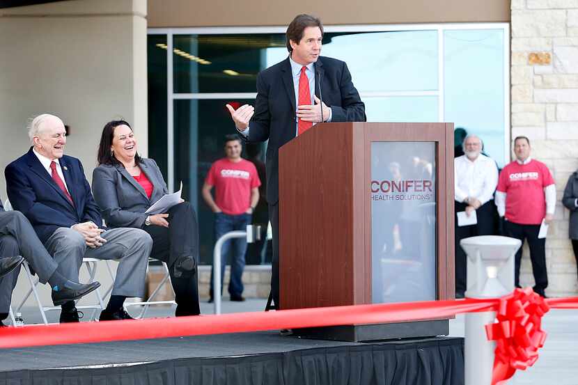 Tony Felker (center), president of the Frisco Chamber of Commerce speaks during a ribbon...